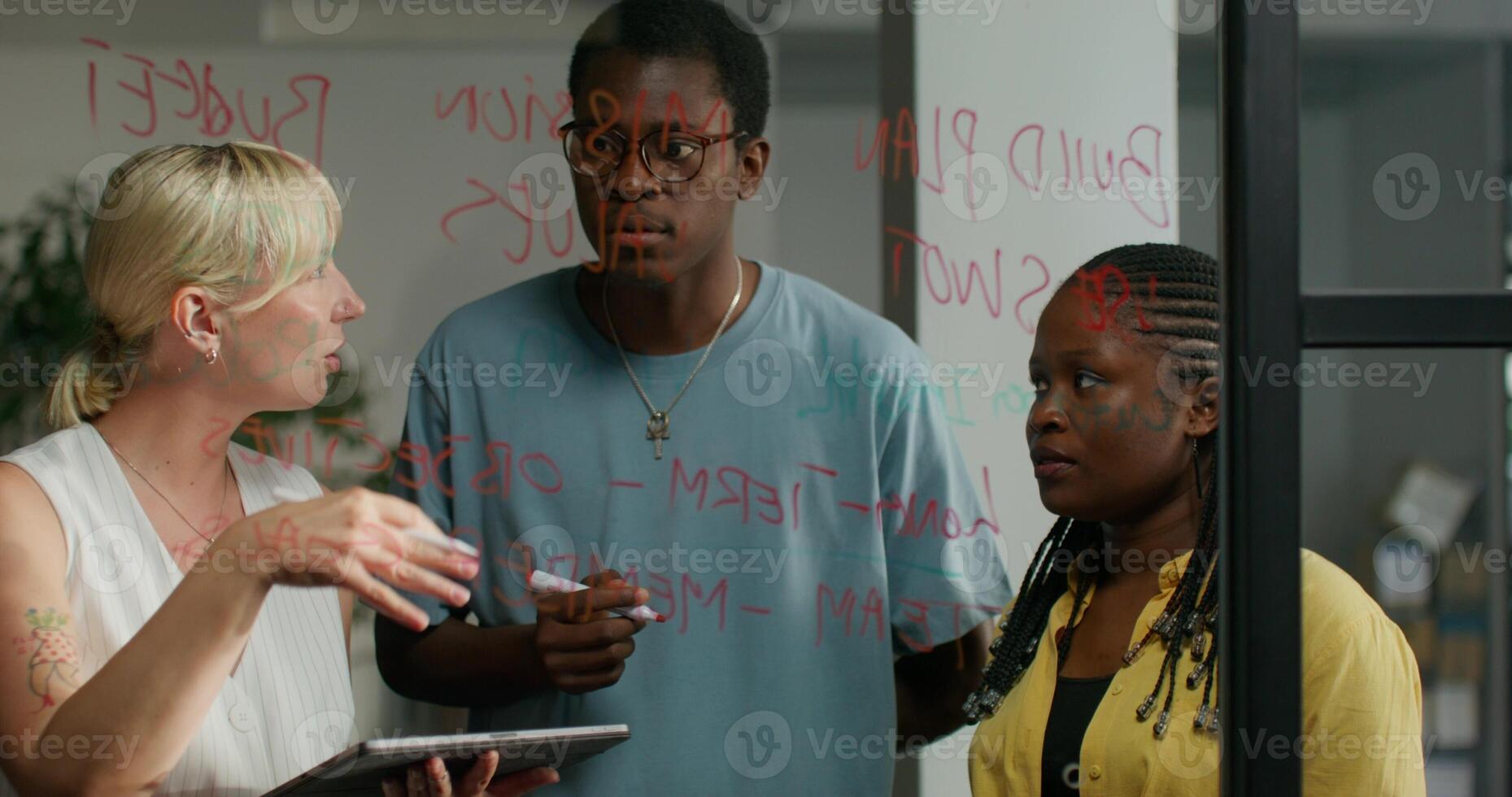 Three people standing in front of a glass wall with writing on it photo