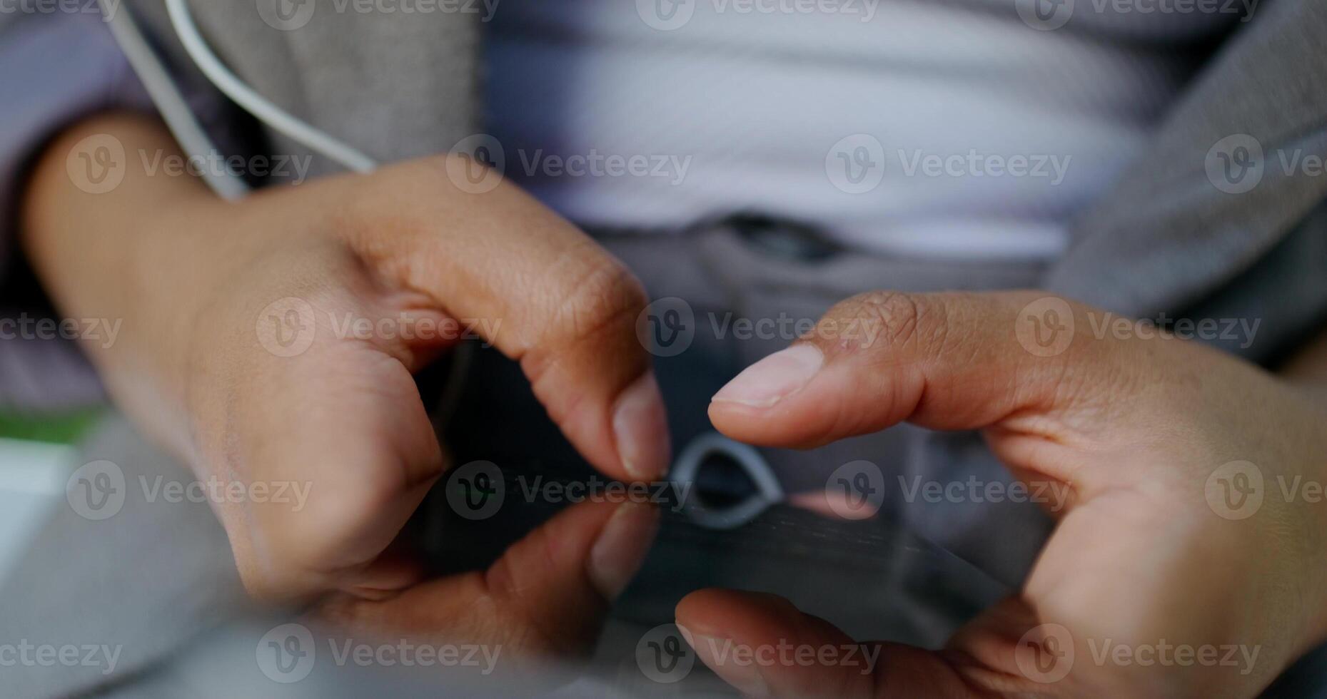 A person holding a cell phone with ear buds photo