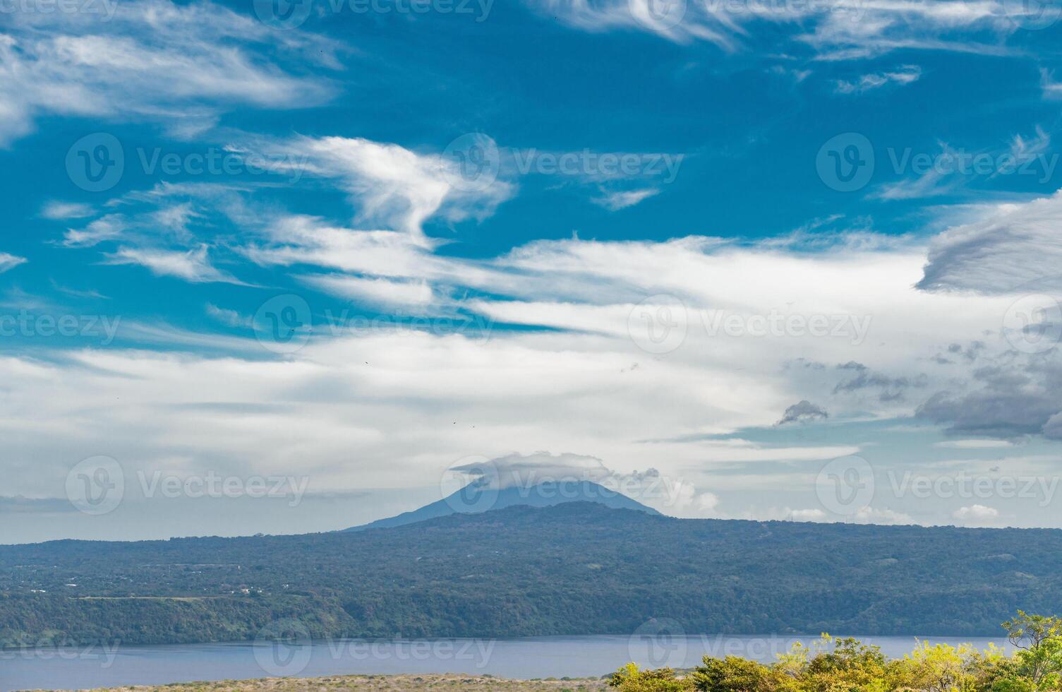 View of a beautiful volcano on a sunny day surrounded by vegetation. Landscape of a volcano with a blue sky surrounded by green vegetation, Nicaragua photo