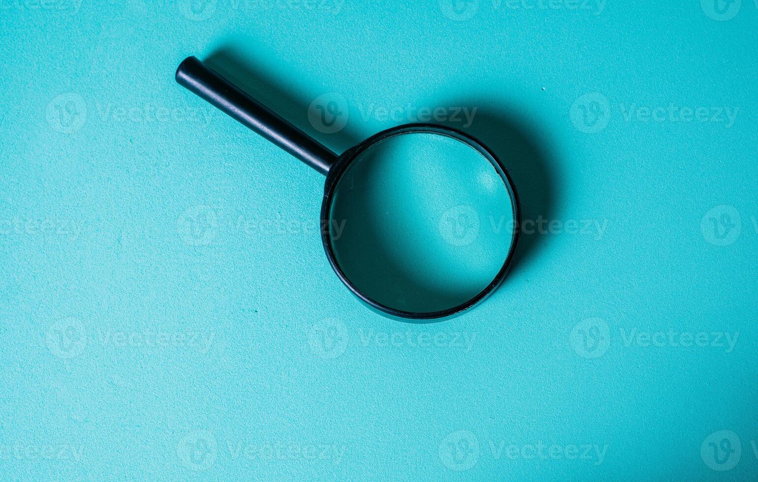 Magnifying Glass on Teal Background for Investigation Concept. CloseUp of Magnifying Glass for Search and Discovery Theme photo