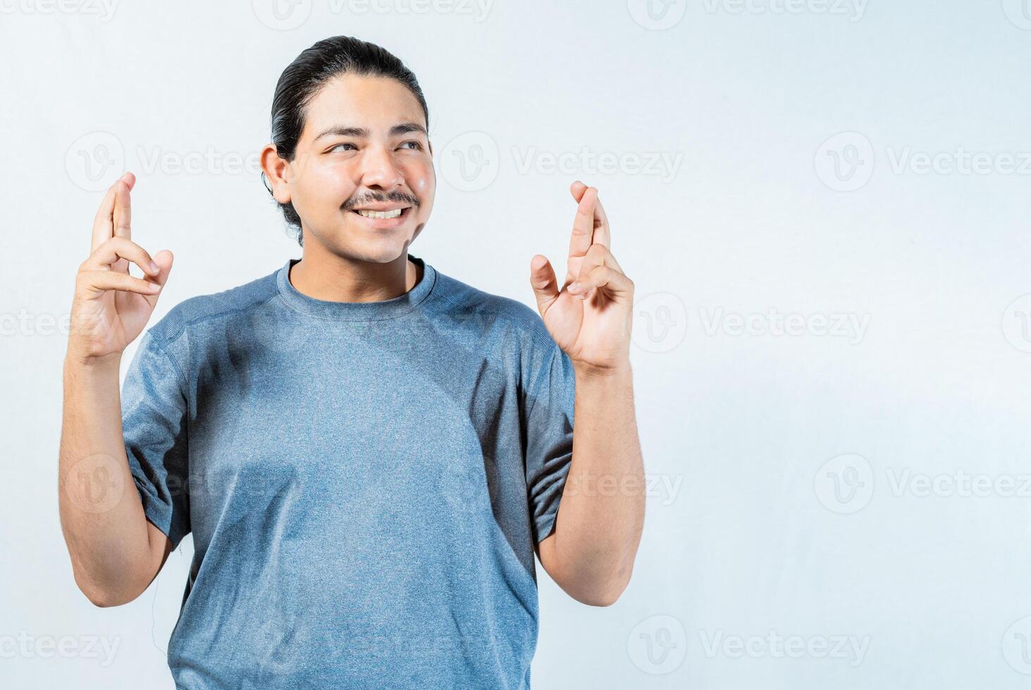 Hopeful man making a wish with fingers isolated. Optimistic guy smiling and making a wish isolated photo