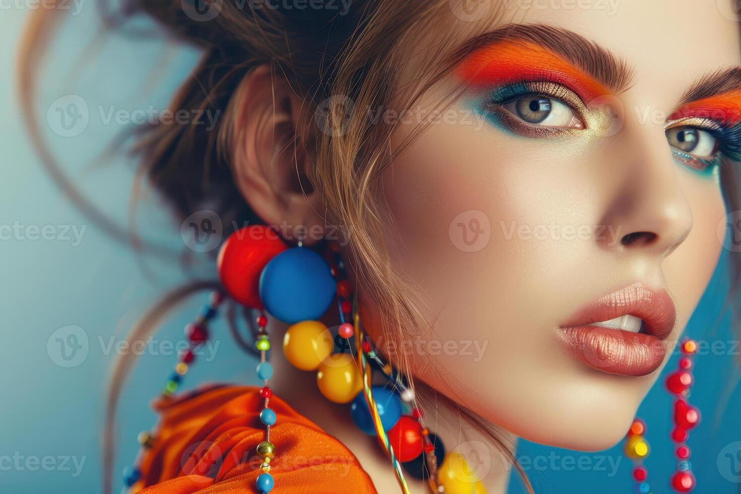 Vibrant makeup on young model with colorful earrings on blue background photo