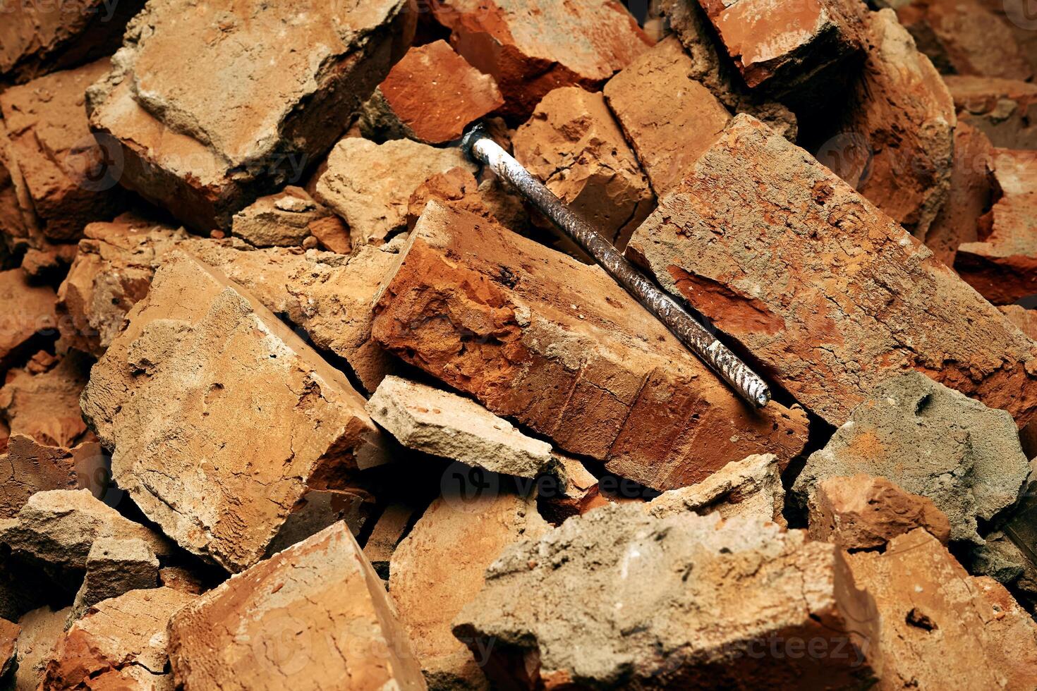Long rusty metal bolt reinforcement among broken bricks photo