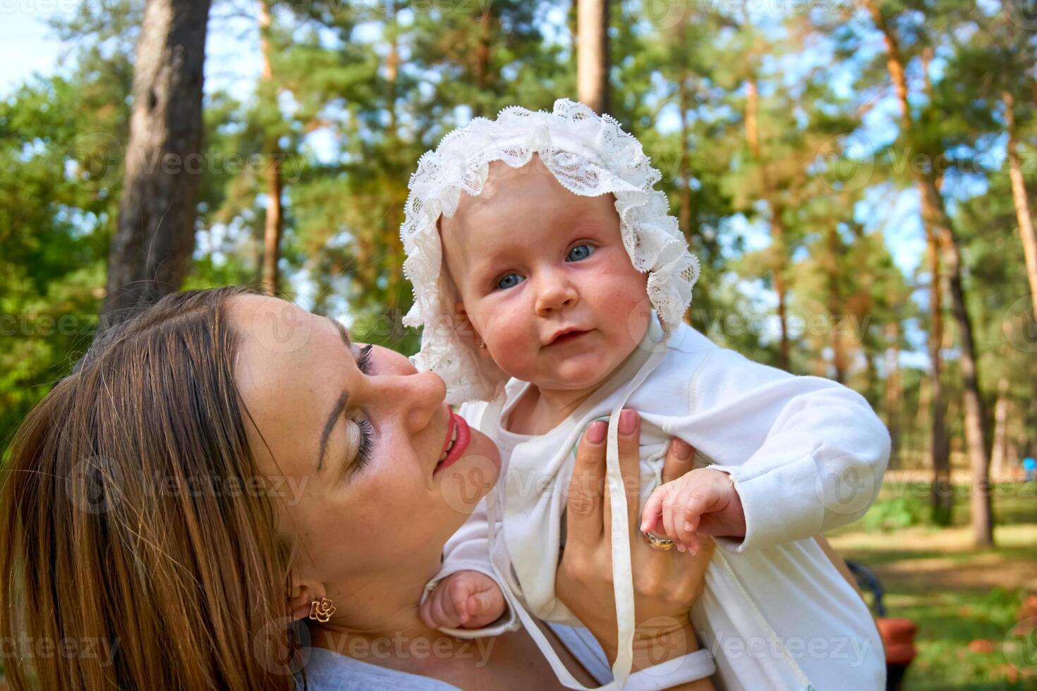 Young happy mother with a cute breast newborn baby in a sunny forest photo