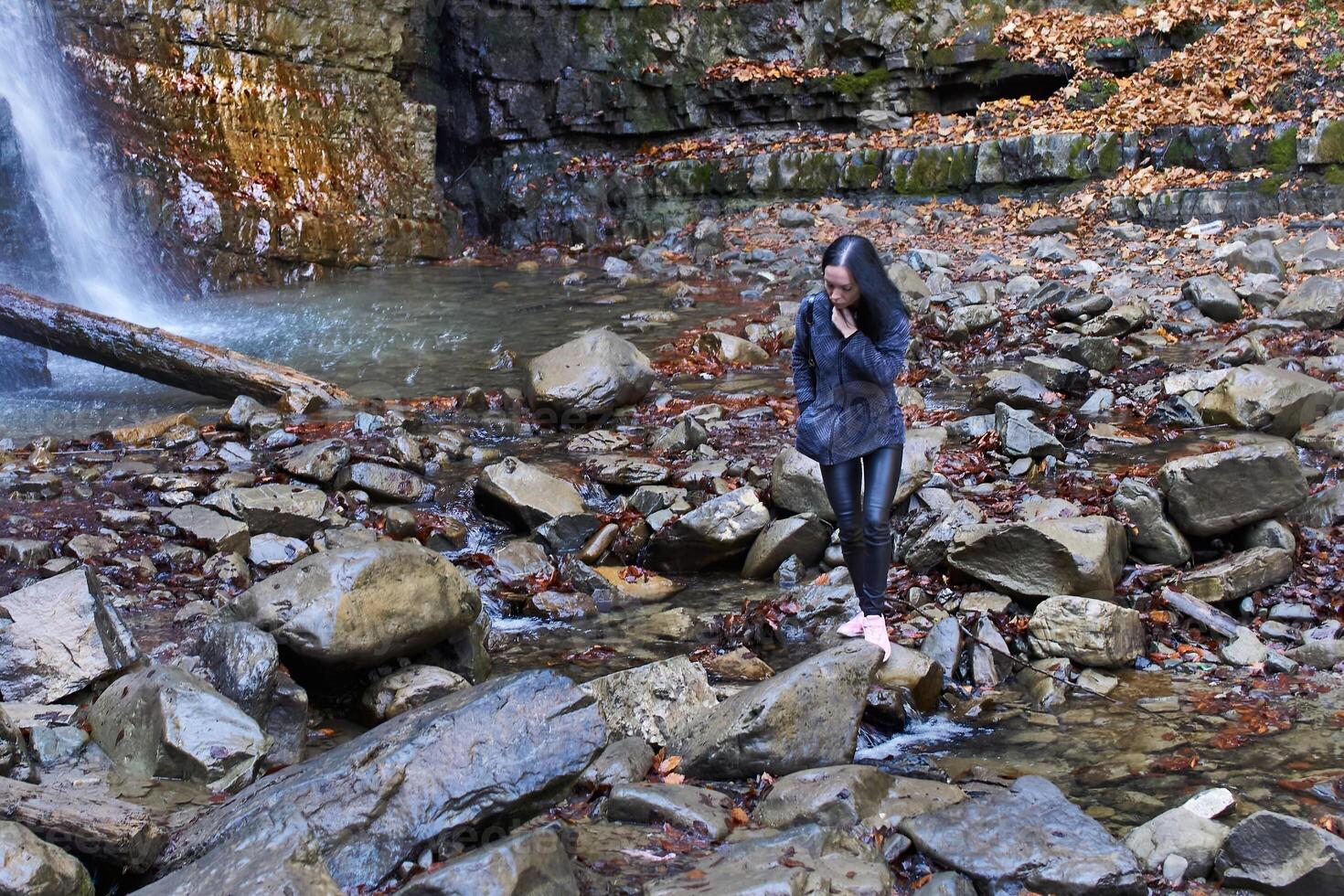 Young woman tourist near mountain waterfall with clear water photo