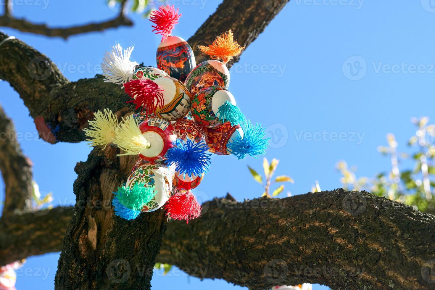 Holiday bunch of colorful painted Easter eggs on green spring tree photo