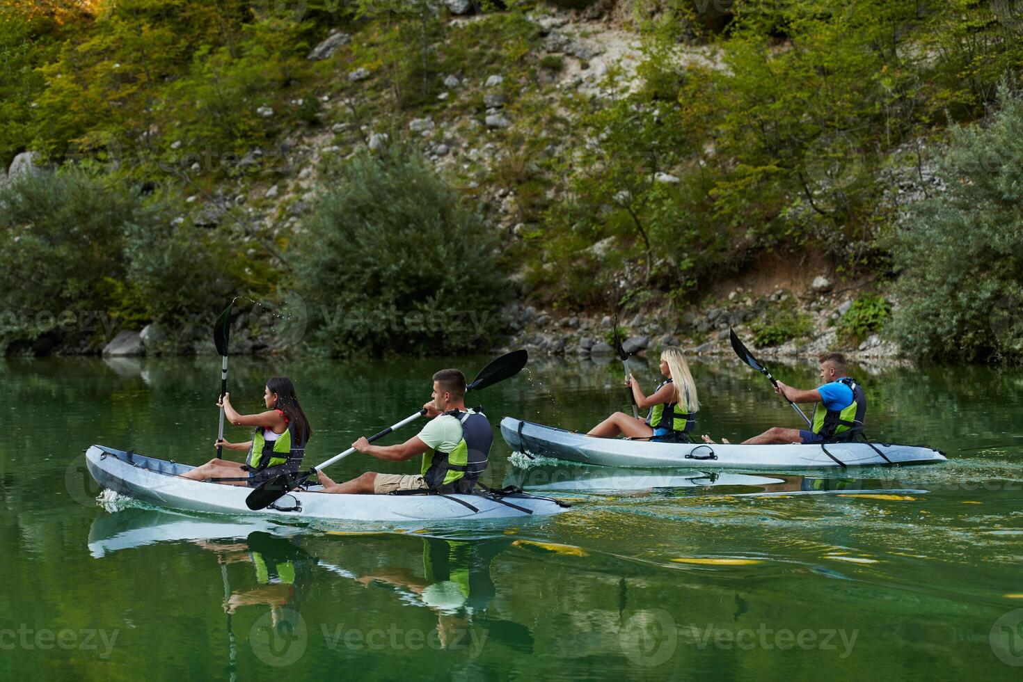 A group of friends enjoying having fun and kayaking while exploring the calm river, surrounding forest and large natural river canyons photo