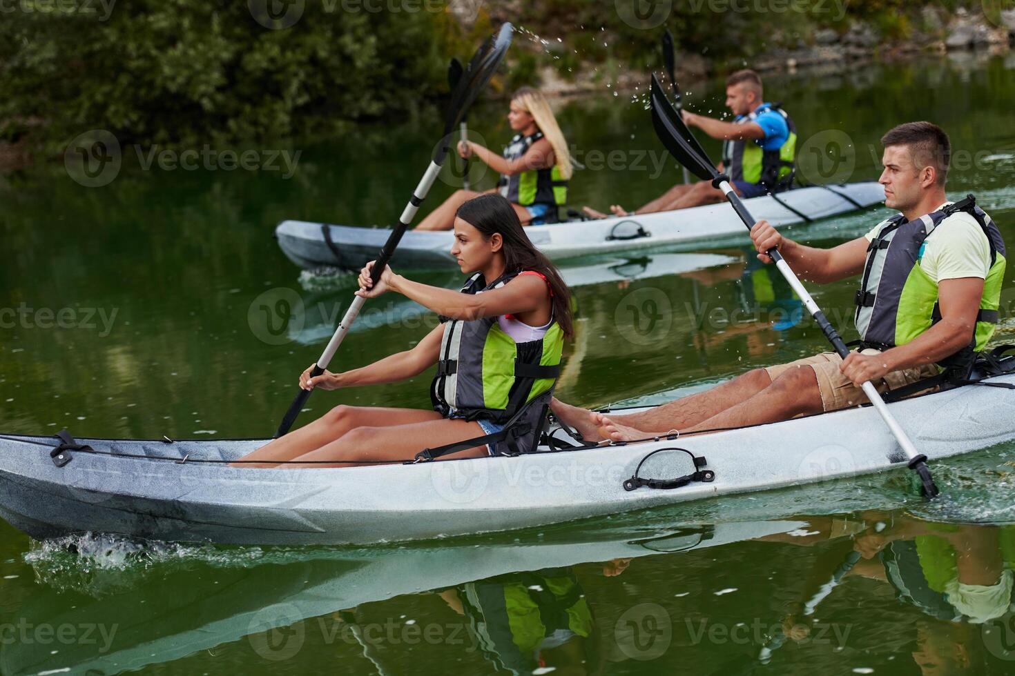 A group of friends enjoying having fun and kayaking while exploring the calm river, surrounding forest and large natural river canyons photo