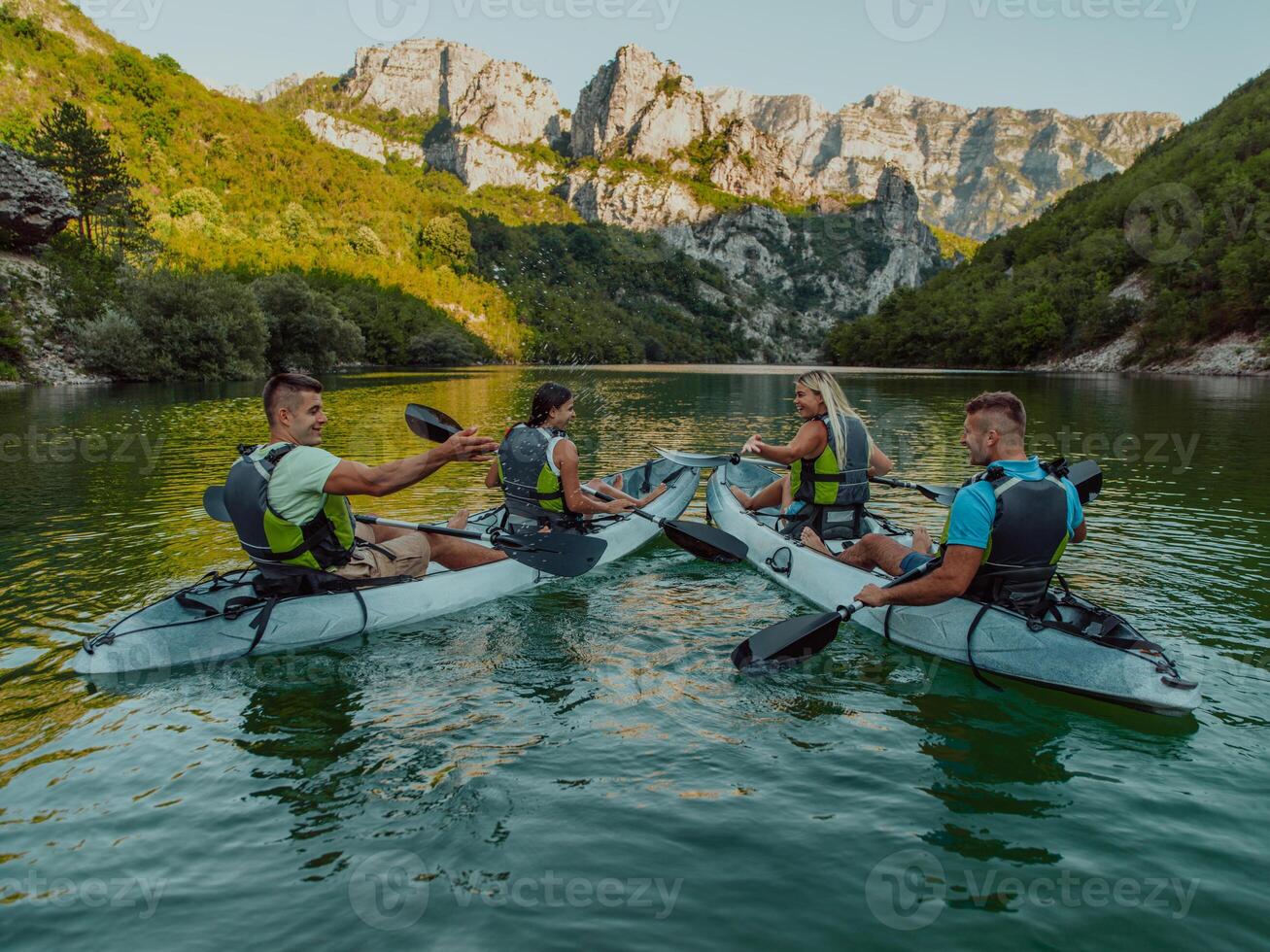 A group of friends enjoying having fun and kayaking while exploring the calm river, surrounding forest and large natural river canyons photo