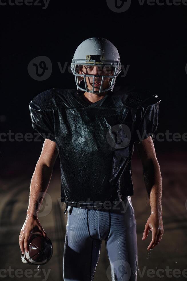 American Football Field. Lonely Athlete Warrior Standing on a Field Holds his Helmet and Ready to Play. Player Preparing to Run, Attack and Score Touchdown. photo