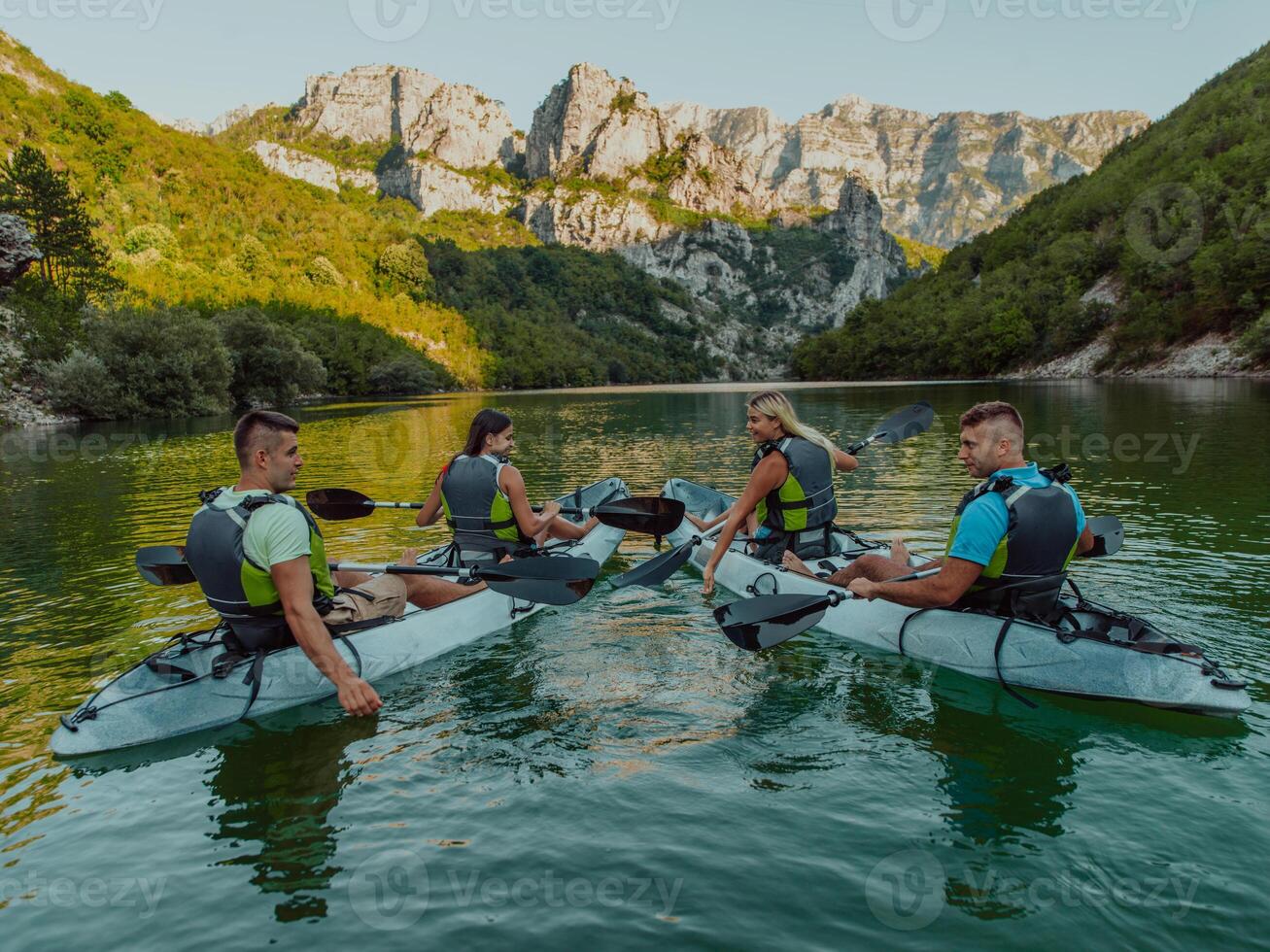 A group of friends enjoying having fun and kayaking while exploring the calm river, surrounding forest and large natural river canyons photo