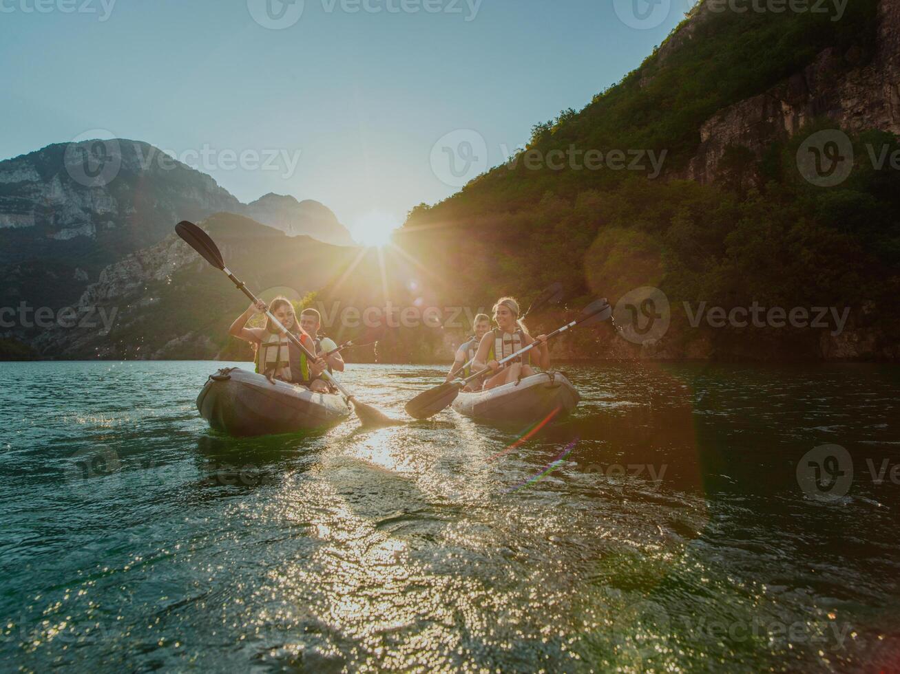 A group of friends enjoying fun and kayaking exploring the calm river, surrounding forest and large natural river canyons during an idyllic sunset. photo