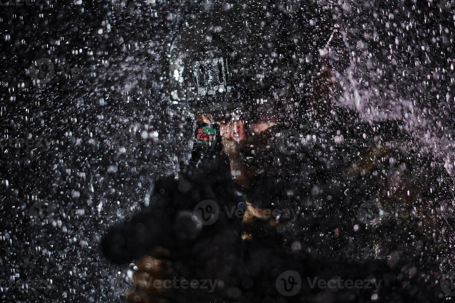 Army soldier in Combat Uniforms with an assault rifle, plate carrier and combat helmet going on a dangerous mission on a rainy night. photo