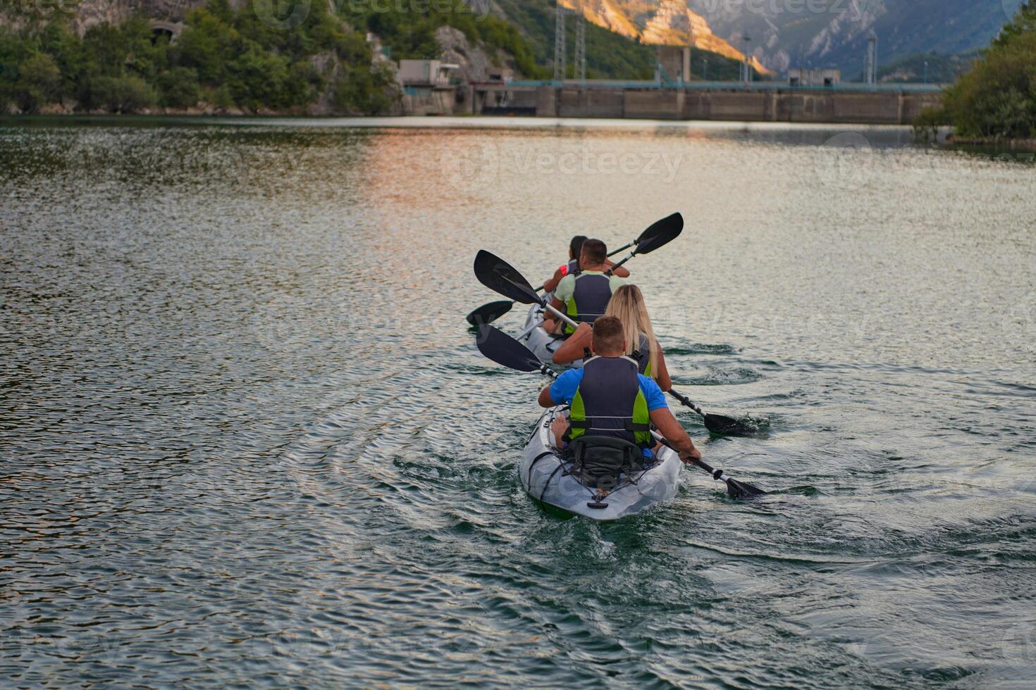 A group of friends enjoying having fun and kayaking while exploring the calm river, surrounding forest and large natural river canyons photo
