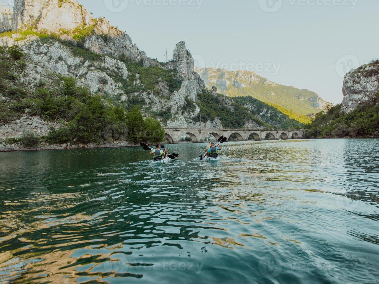 A group of friends enjoying having fun and kayaking while exploring the calm river, surrounding forest and large natural river canyons photo