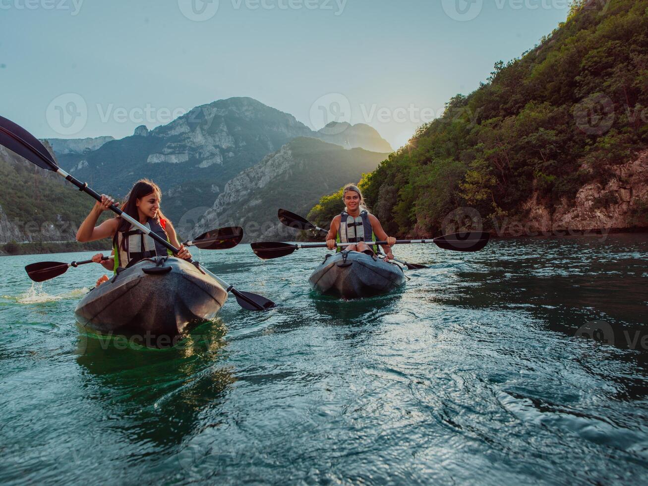 A group of friends enjoying fun and kayaking exploring the calm river, surrounding forest and large natural river canyons during an idyllic sunset. photo