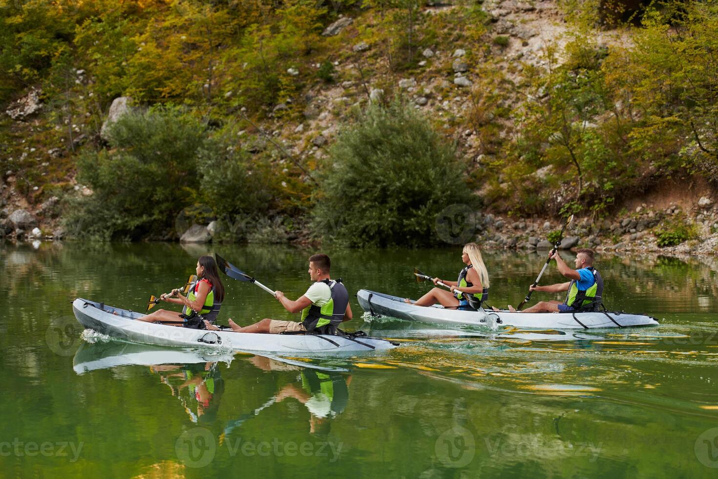 A group of friends enjoying having fun and kayaking while exploring the calm river, surrounding forest and large natural river canyons photo