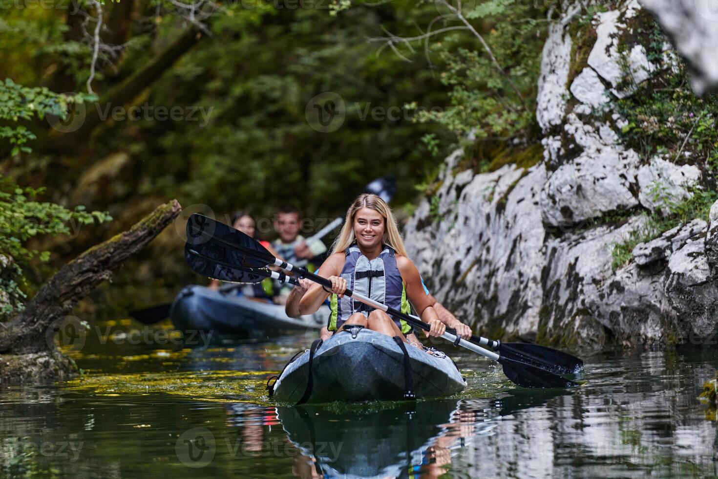 A group of friends enjoying having fun and kayaking while exploring the calm river, surrounding forest and large natural river canyons photo