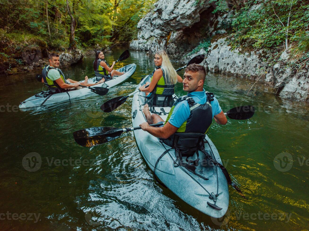 A group of friends enjoying having fun and kayaking while exploring the calm river, surrounding forest and large natural river canyons photo