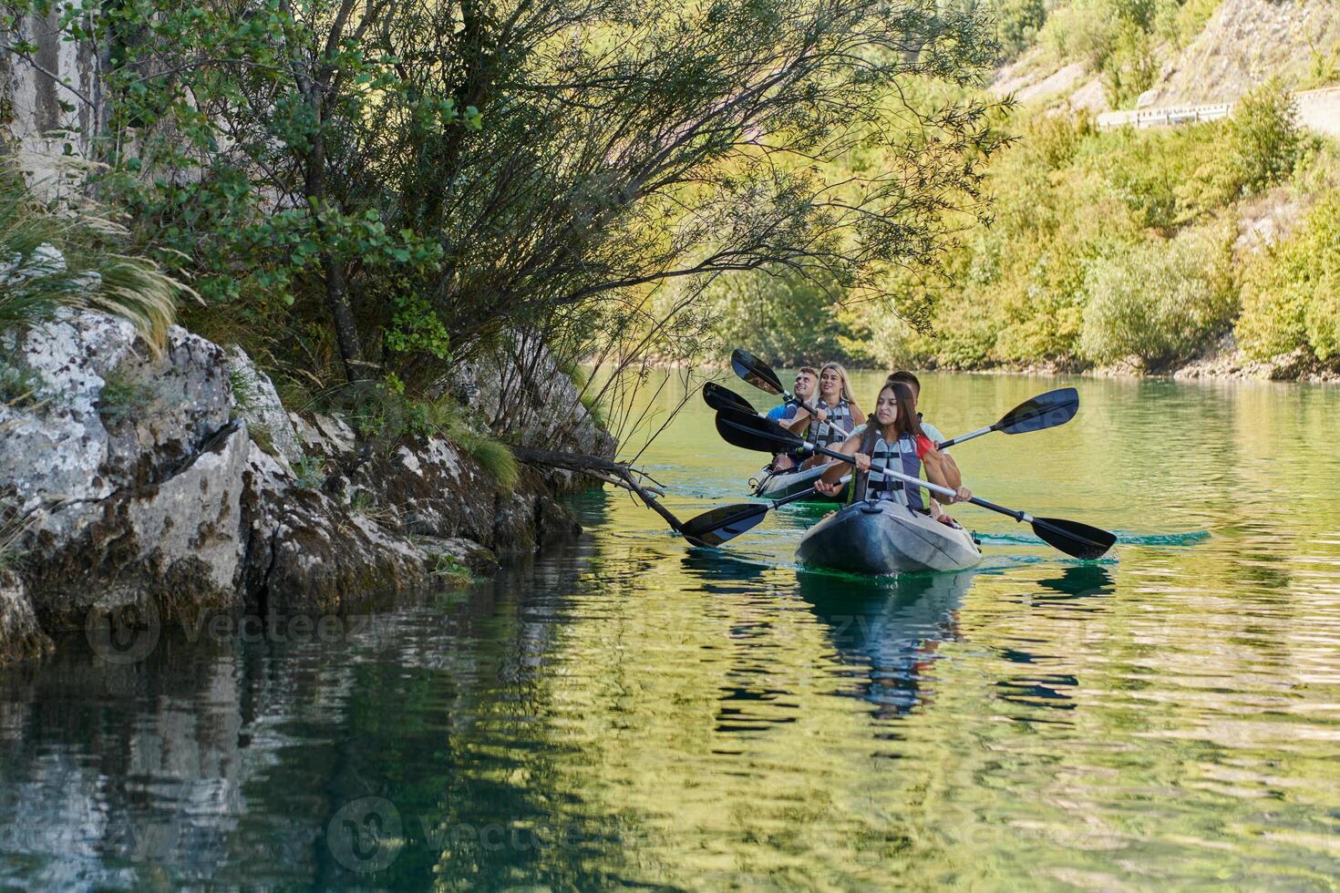 A group of friends enjoying having fun and kayaking while exploring the calm river, surrounding forest and large natural river canyons photo