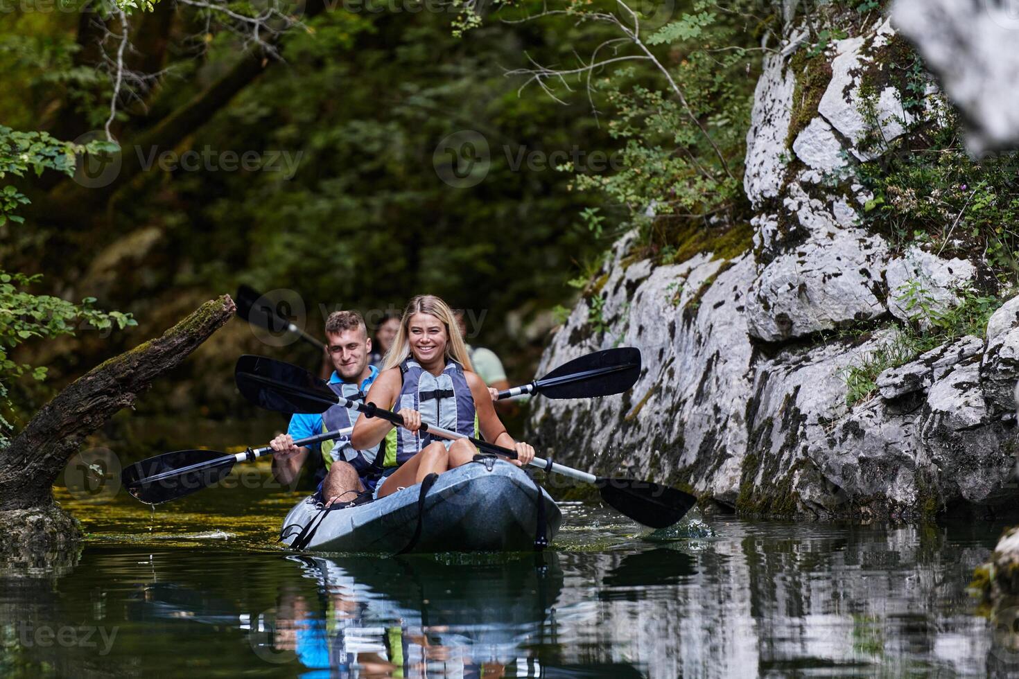 A group of friends enjoying having fun and kayaking while exploring the calm river, surrounding forest and large natural river canyons photo