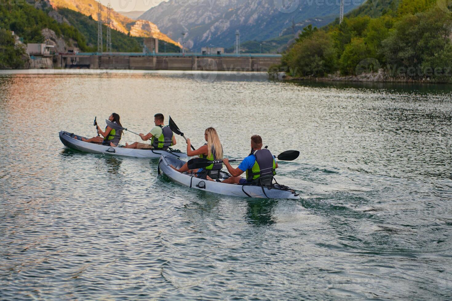 A group of friends enjoying having fun and kayaking while exploring the calm river, surrounding forest and large natural river canyons photo