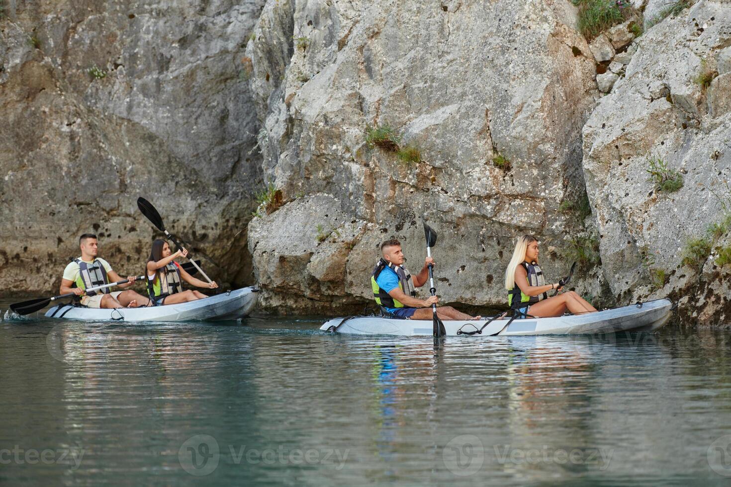 A group of friends enjoying having fun and kayaking while exploring the calm river, surrounding forest and large natural river canyons photo