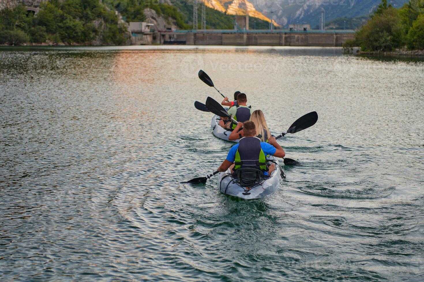 A group of friends enjoying having fun and kayaking while exploring the calm river, surrounding forest and large natural river canyons photo