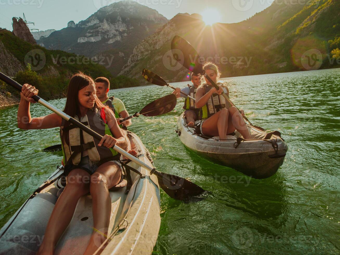 A group of friends enjoying fun and kayaking exploring the calm river, surrounding forest and large natural river canyons during an idyllic sunset. photo