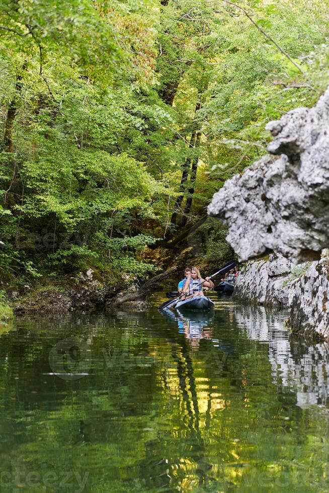 A group of friends enjoying having fun and kayaking while exploring the calm river, surrounding forest and large natural river canyons photo