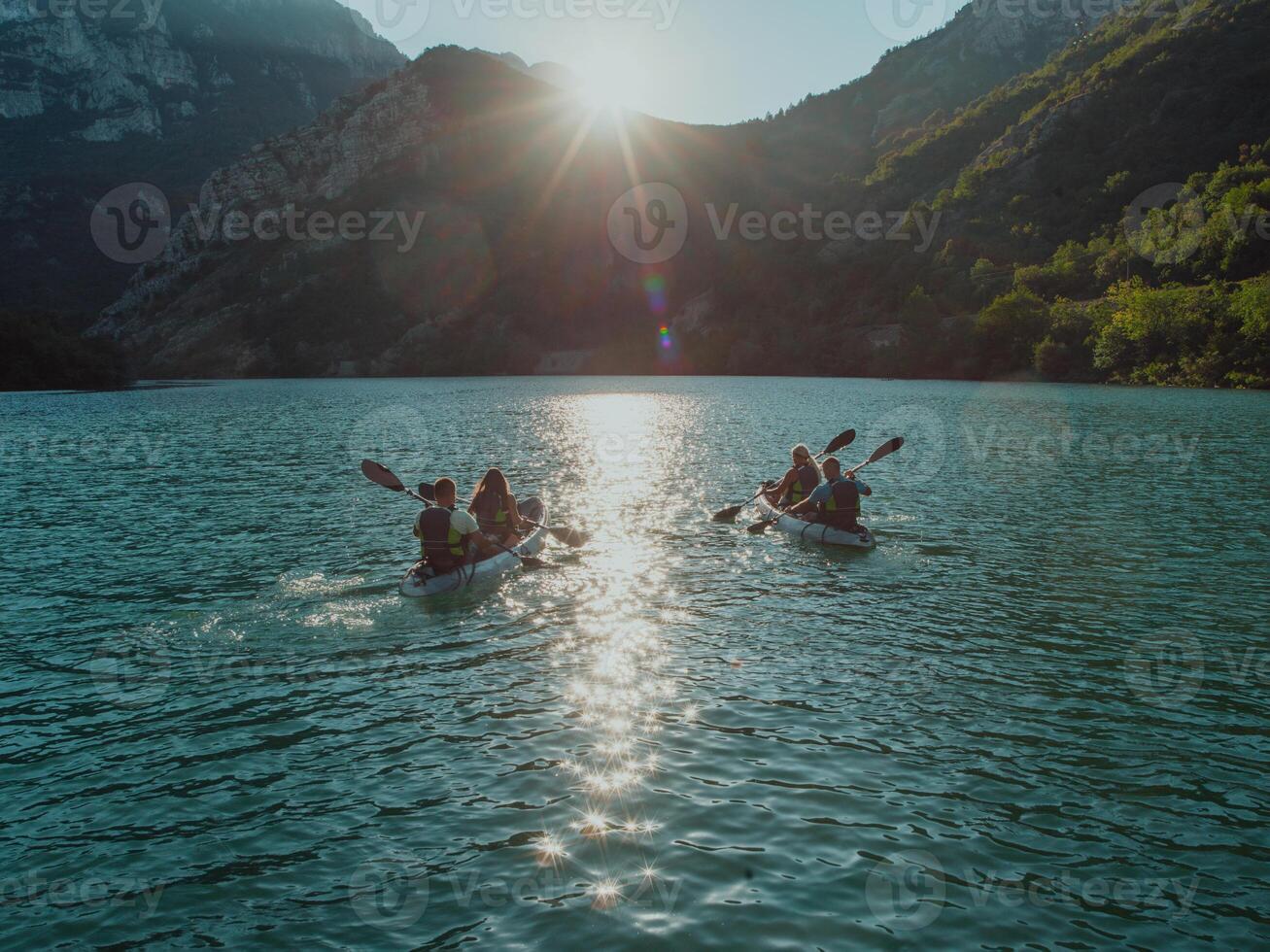 A group of friends enjoying fun and kayaking exploring the calm river, surrounding forest and large natural river canyons during an idyllic sunset. photo