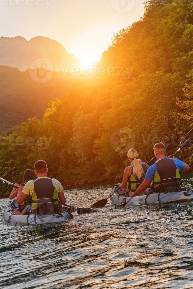 A group of friends enjoying fun and kayaking exploring the calm river, surrounding forest and large natural river canyons during an idyllic sunset. photo