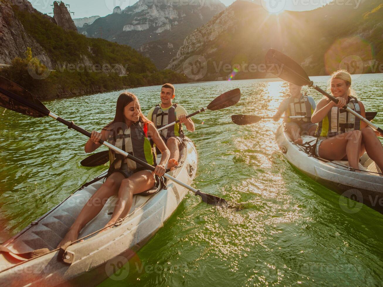A group of friends enjoying fun and kayaking exploring the calm river, surrounding forest and large natural river canyons during an idyllic sunset. photo
