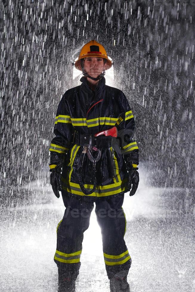 A determined female firefighter in a professional uniform striding through the dangerous, rainy night on a daring rescue mission, showcasing her unwavering bravery and commitment to saving lives. photo