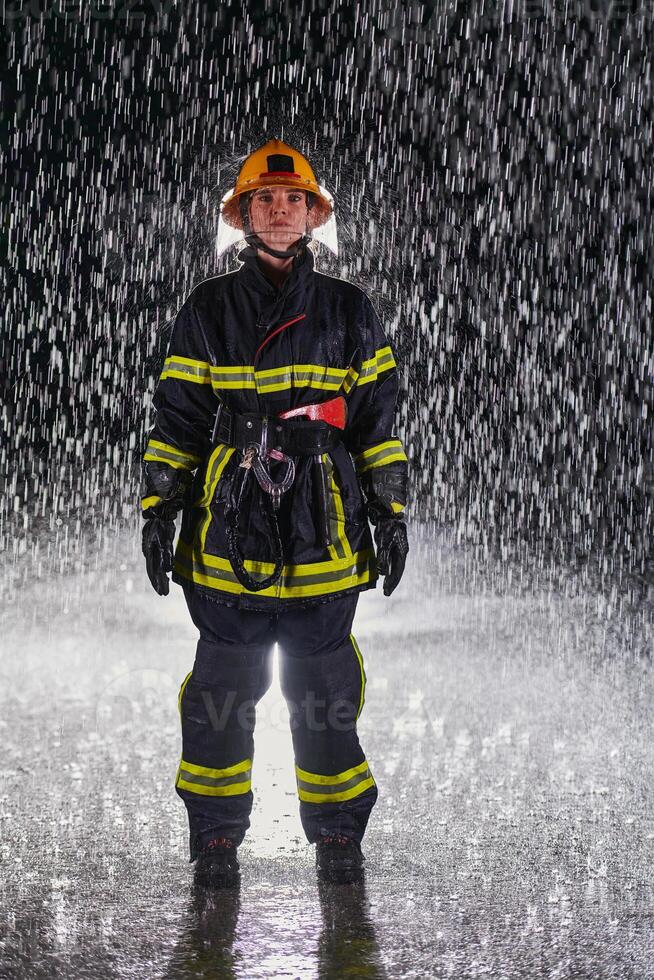 A determined female firefighter in a professional uniform striding through the dangerous, rainy night on a daring rescue mission, showcasing her unwavering bravery and commitment to saving lives. photo
