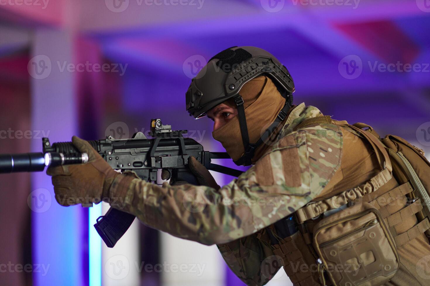 A professional soldier undertakes a perilous mission in an abandoned building illuminated by neon blue and purple lights photo
