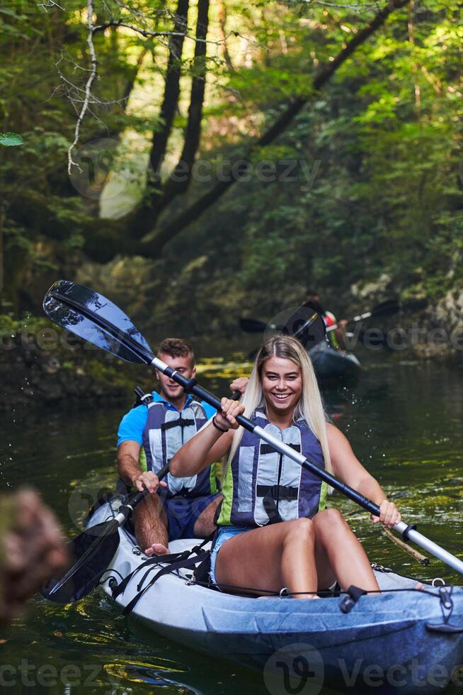 A group of friends enjoying having fun and kayaking while exploring the calm river, surrounding forest and large natural river canyons photo