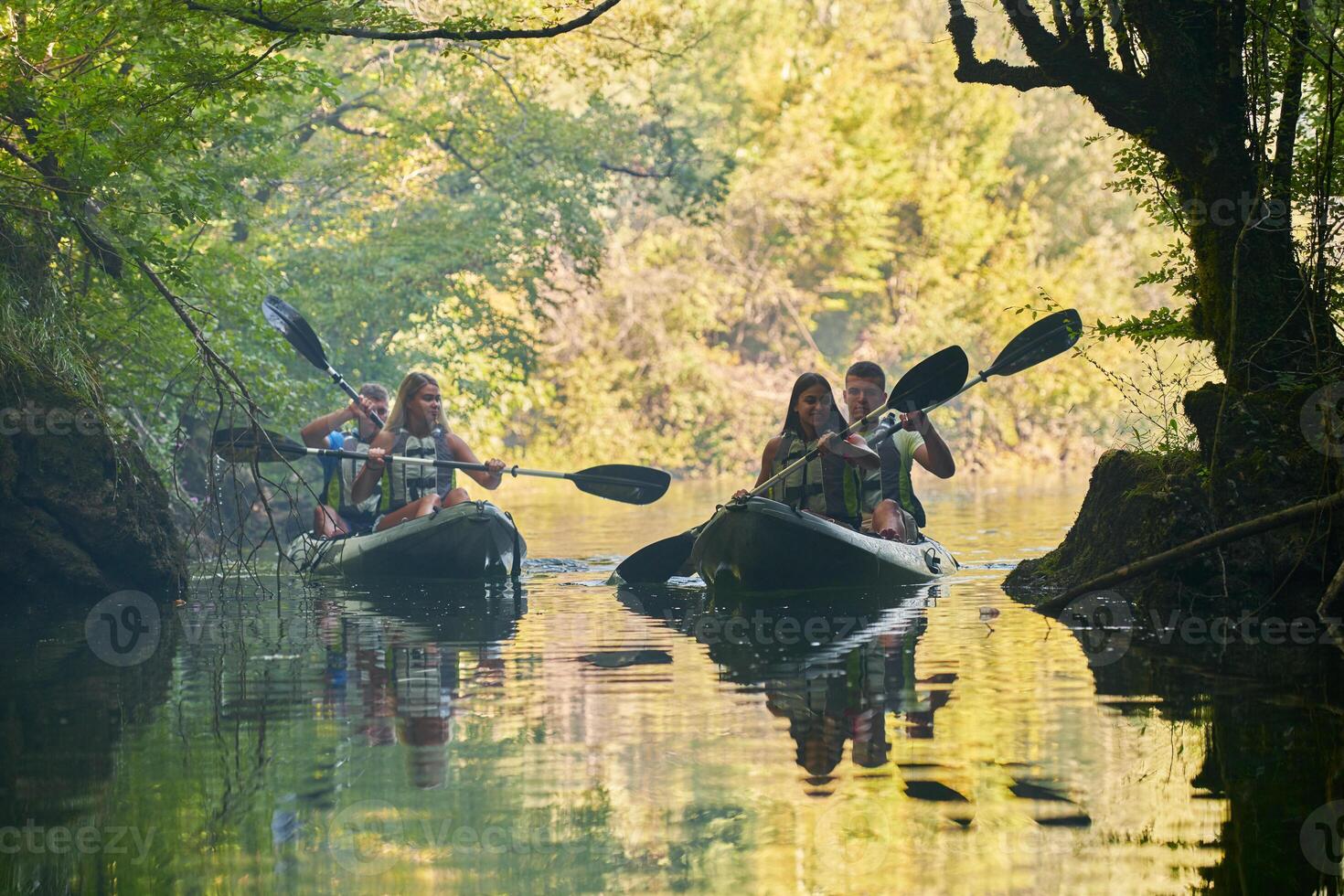 A group of friends enjoying having fun and kayaking while exploring the calm river, surrounding forest and large natural river canyons photo
