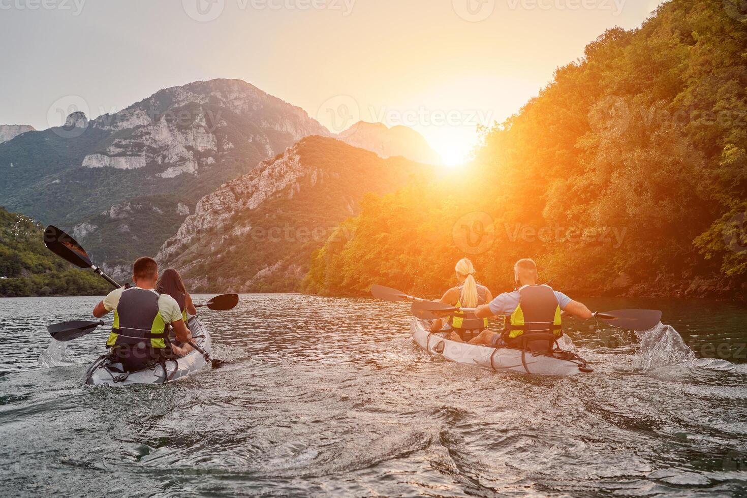 A group of friends enjoying fun and kayaking exploring the calm river, surrounding forest and large natural river canyons during an idyllic sunset. photo