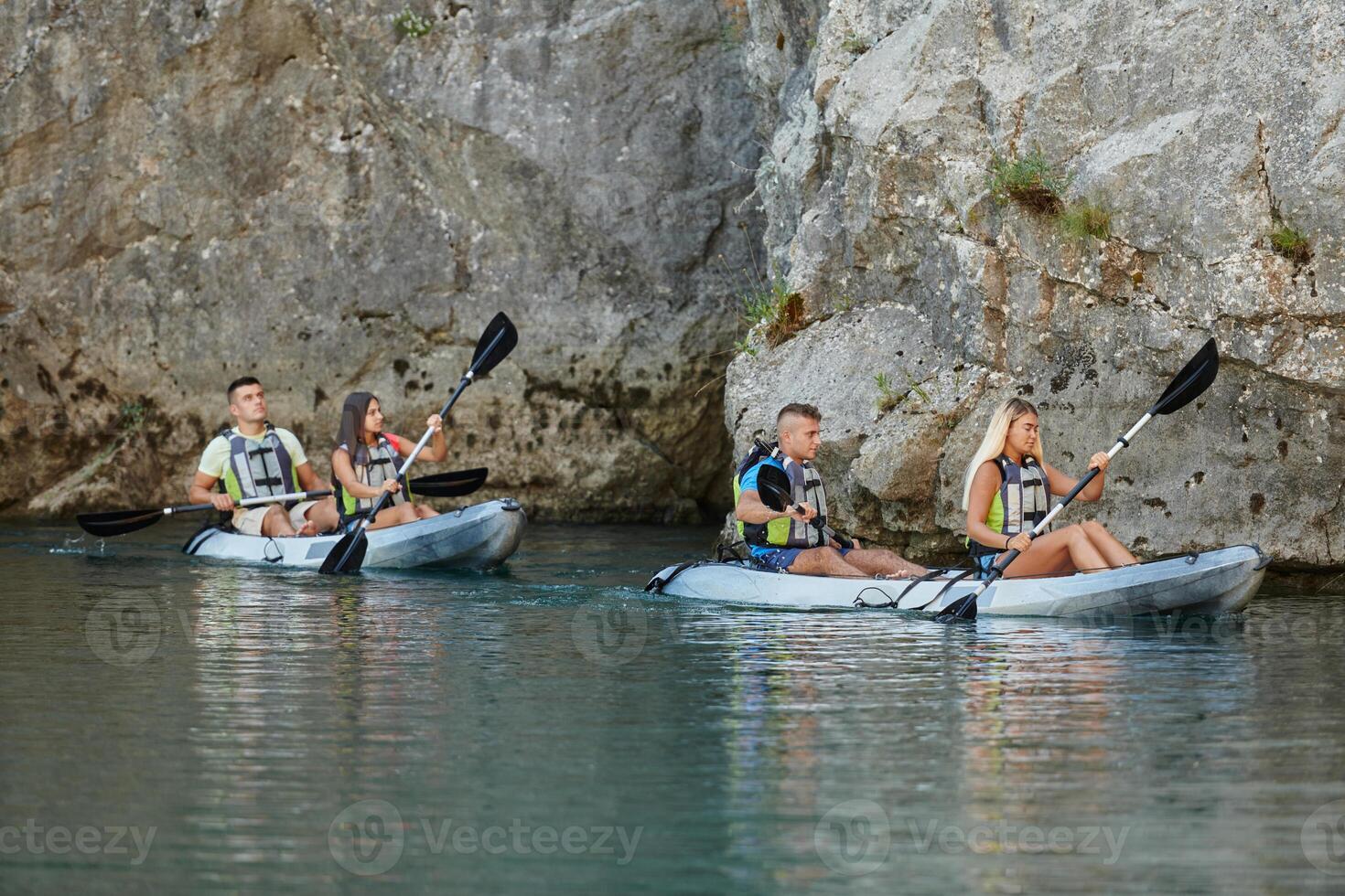 A group of friends enjoying having fun and kayaking while exploring the calm river, surrounding forest and large natural river canyons photo
