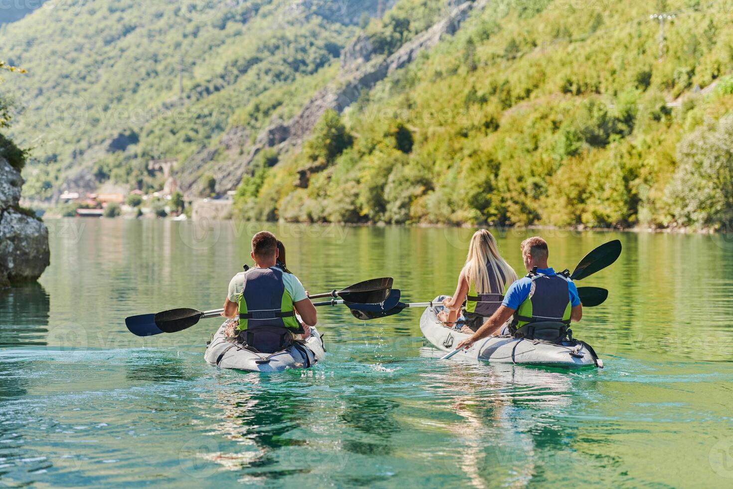 A group of friends enjoying having fun and kayaking while exploring the calm river, surrounding forest and large natural river canyons photo