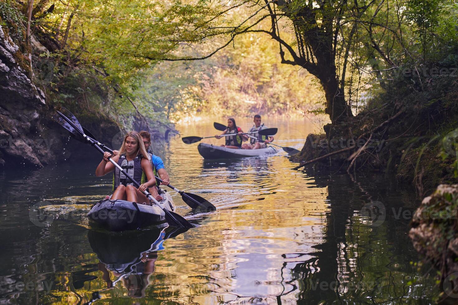 A group of friends enjoying having fun and kayaking while exploring the calm river, surrounding forest and large natural river canyons photo