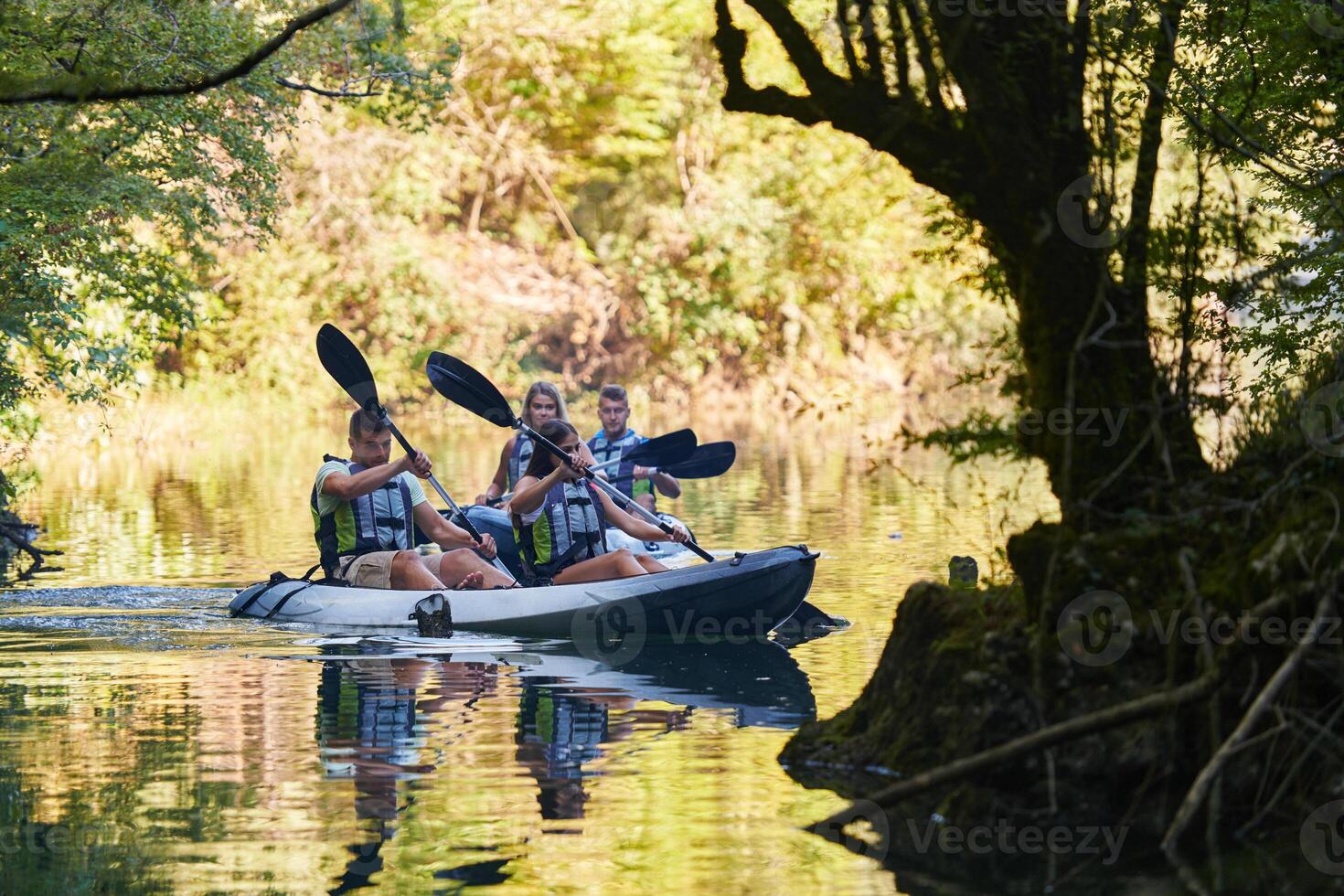 A group of friends enjoying having fun and kayaking while exploring the calm river, surrounding forest and large natural river canyons photo
