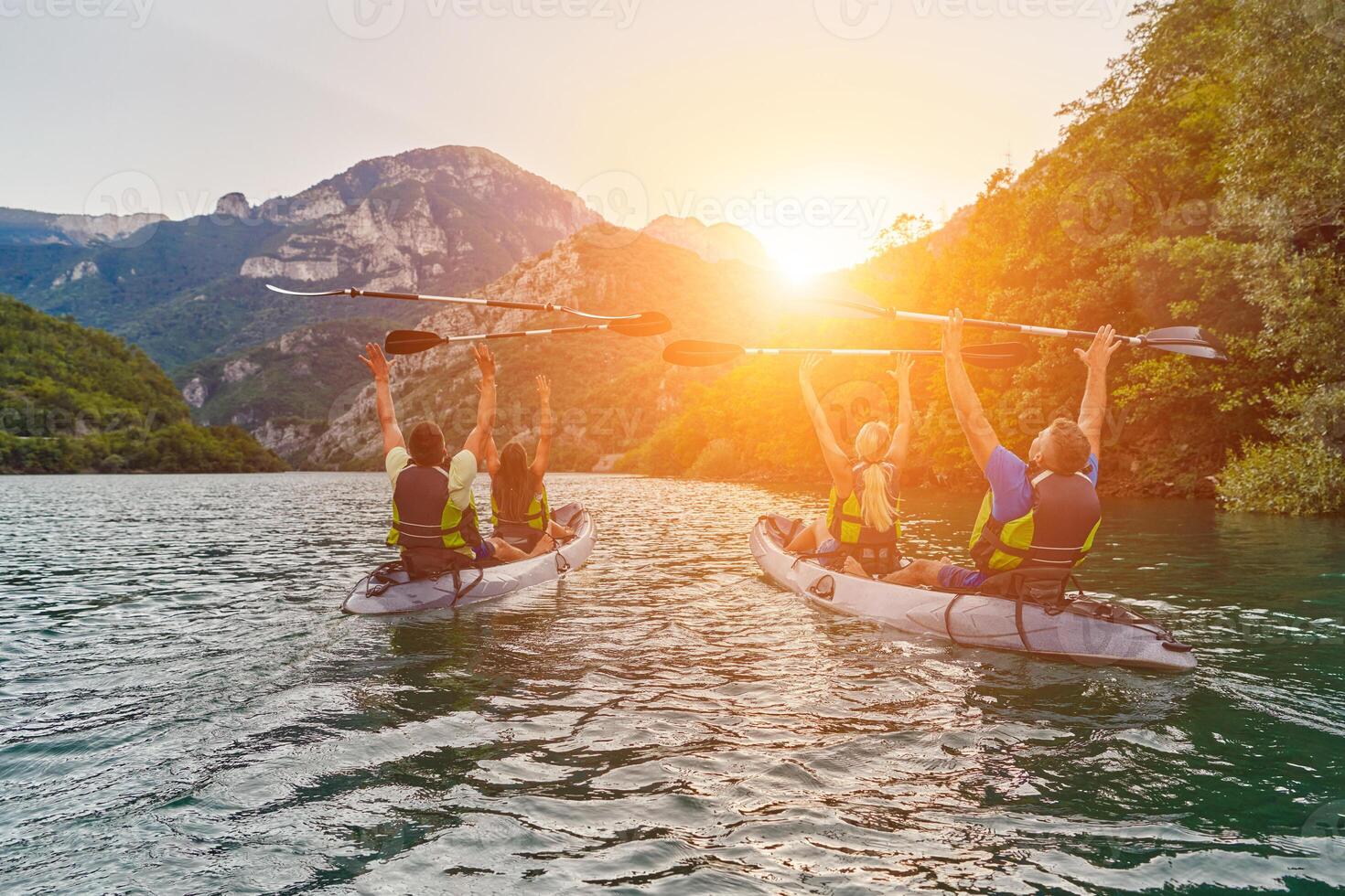 A group of friends enjoying fun and kayaking exploring the calm river, surrounding forest and large natural river canyons during an idyllic sunset. photo
