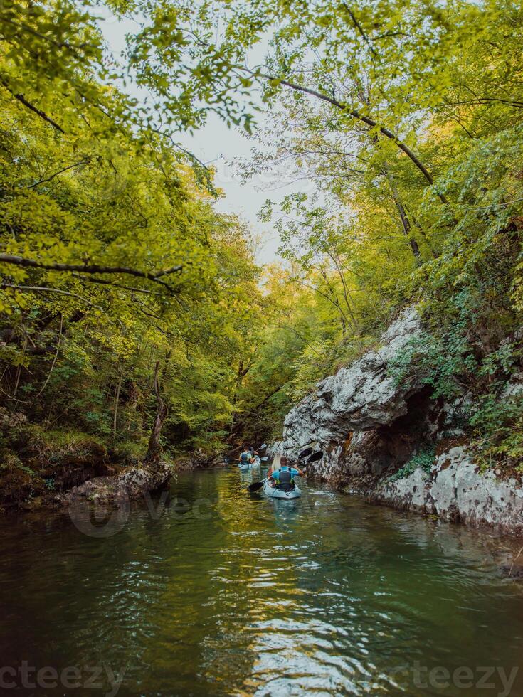 A group of friends enjoying having fun and kayaking while exploring the calm river, surrounding forest and large natural river canyons photo