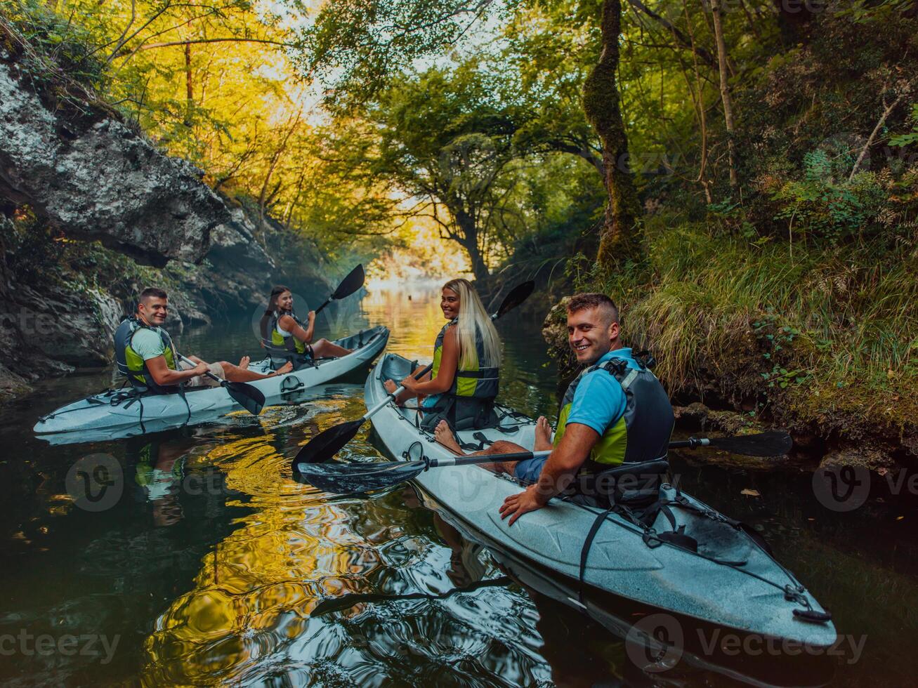 A group of friends enjoying having fun and kayaking while exploring the calm river, surrounding forest and large natural river canyons photo