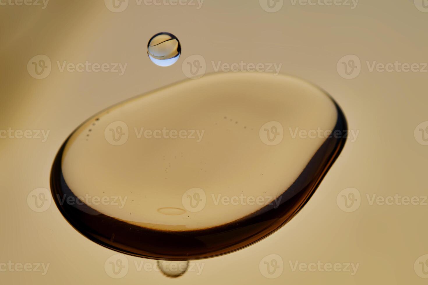 Texture of cosmetic oil with falling drop on golden background. photo