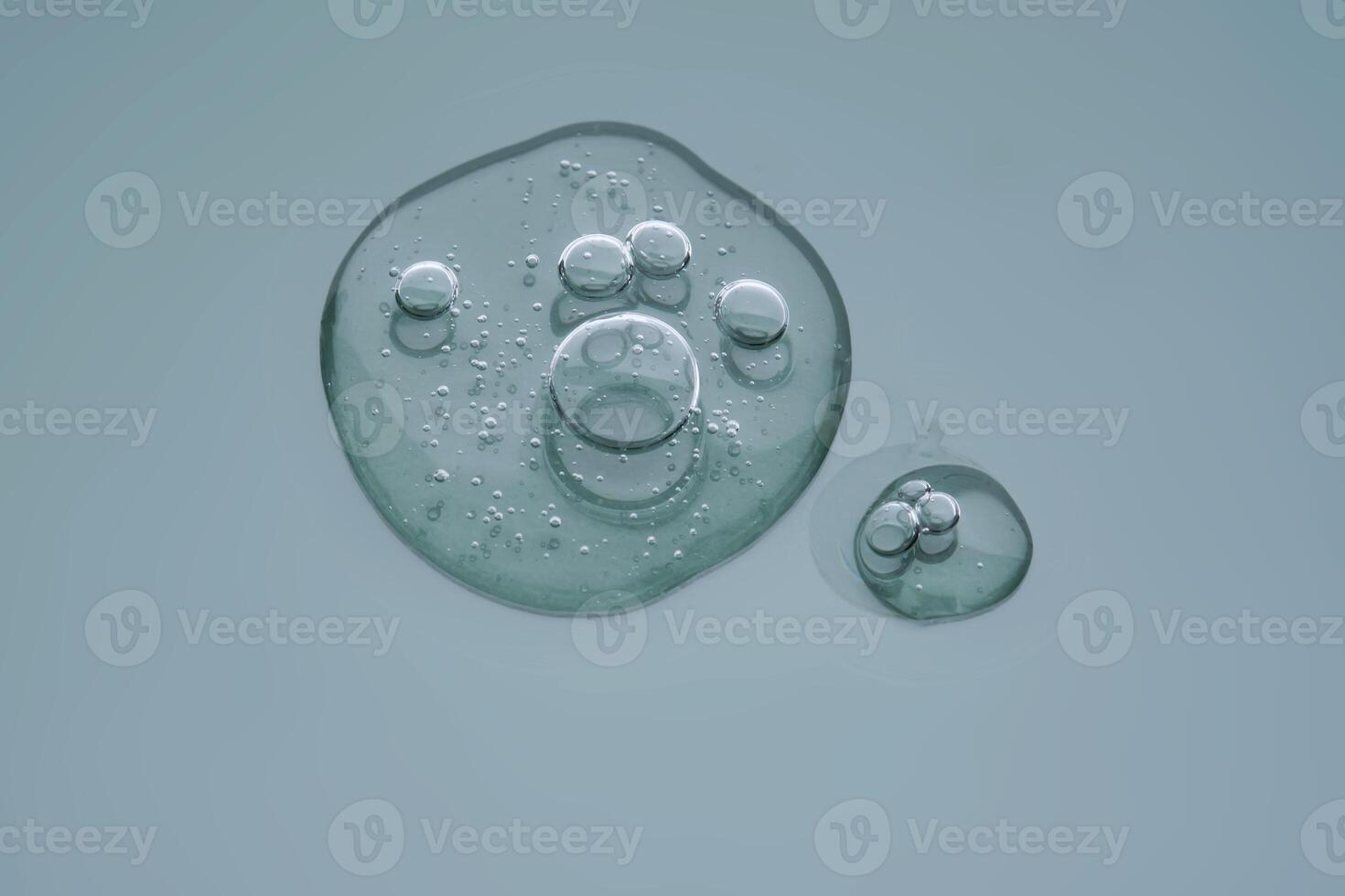Textured round drop of serum with bubbles on dark green background. photo