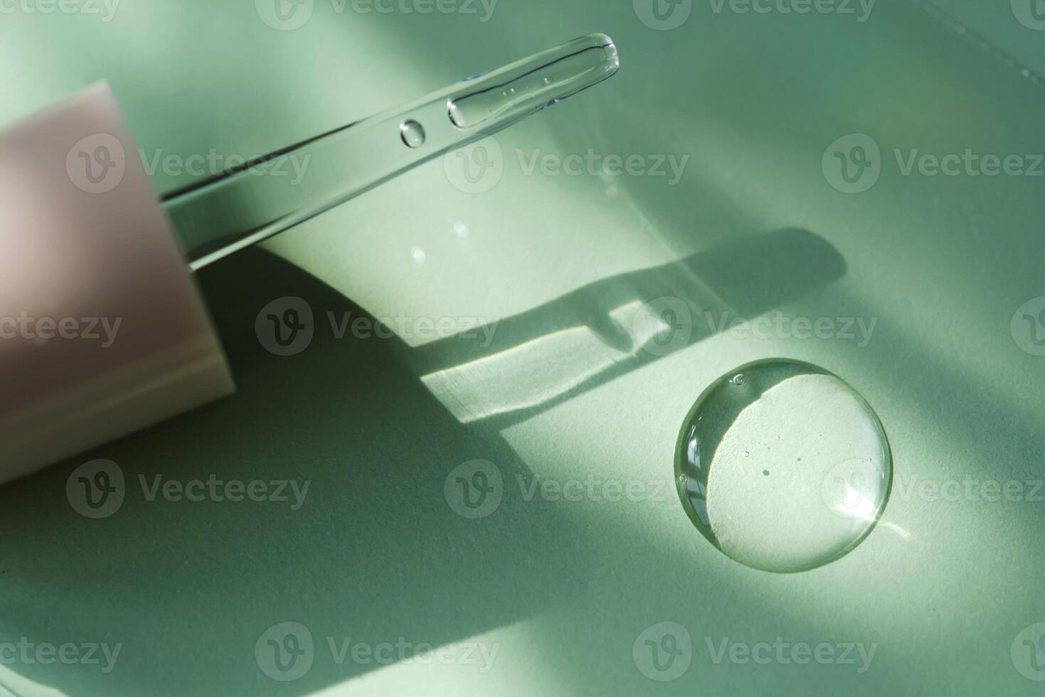 A drop of serum and dropper on a green background. photo