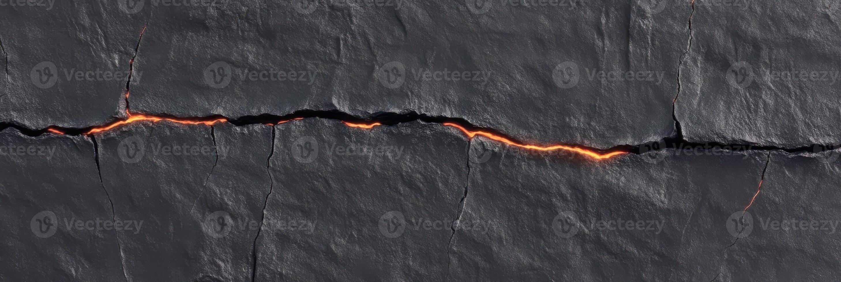 Cracked lava flow with glowing lava illuminating dark basalt surface photo